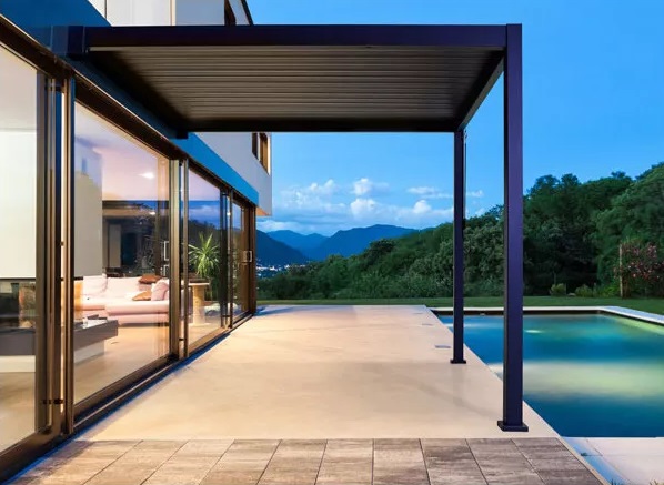 Une pergola bioclimatique adossée en bordure de piscine